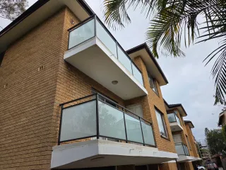 Glass and aluminium balcony balustrade on a brick home